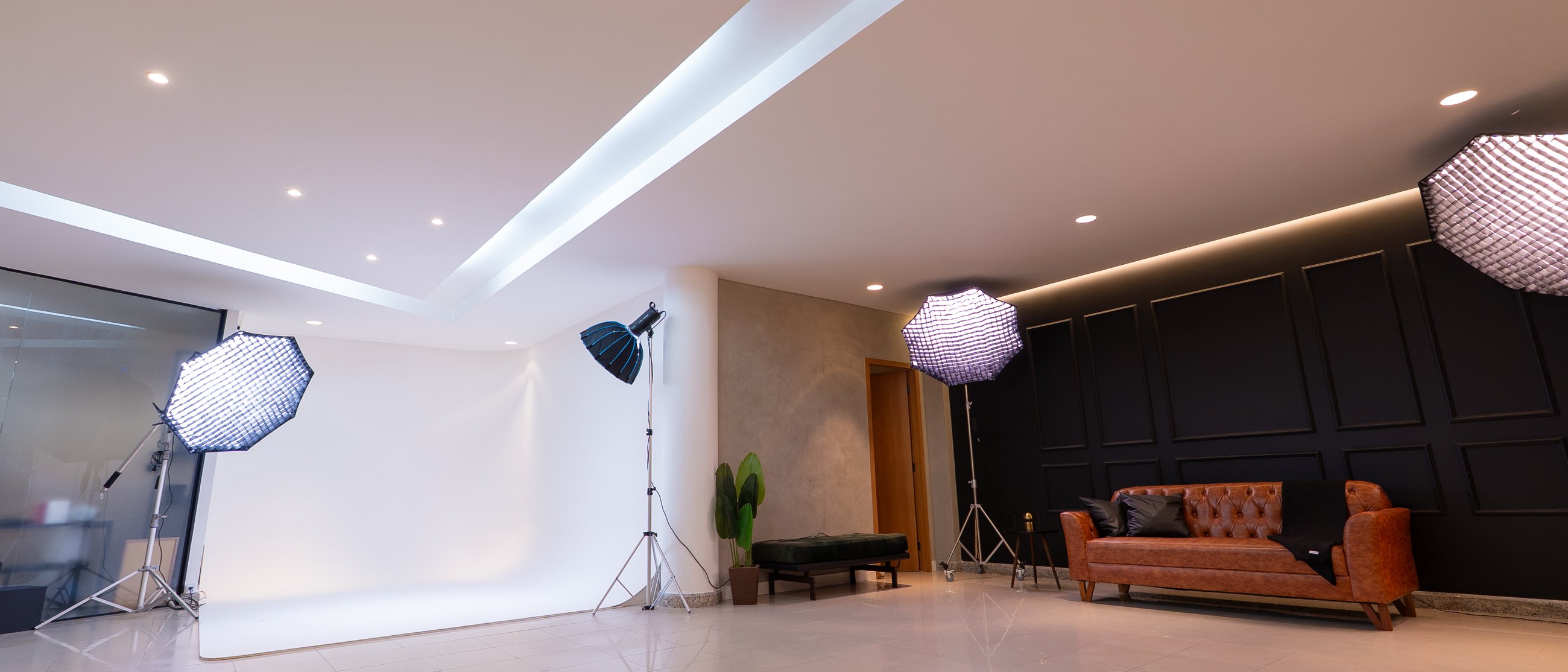 Interior do Studio 091: fundo infinito, parede preta com sofá Chesterfield e iluminação de estúdio